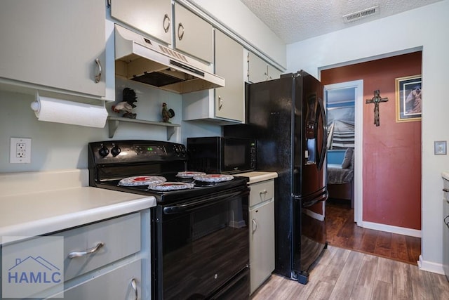 901 Pintail Ct, Hinesville, GA 31313 - kitchen featuring black appliances, under cabinet range hood, light wood-style flooring, light countertops, and a textured ceiling