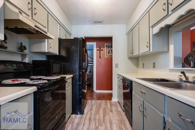 901 Pintail Ct, Hinesville, GA 31313 - kitchen with black appliances, under cabinet range hood, light wood finished floors, a textured ceiling, and gray cabinetry