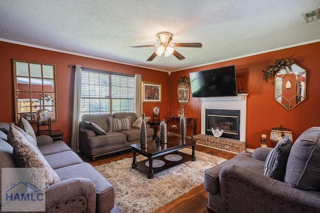 901 Pintail Ct, Hinesville, GA 31313 - living room with ceiling fan, wood finished floors, a textured ceiling, a brick fireplace, and crown molding