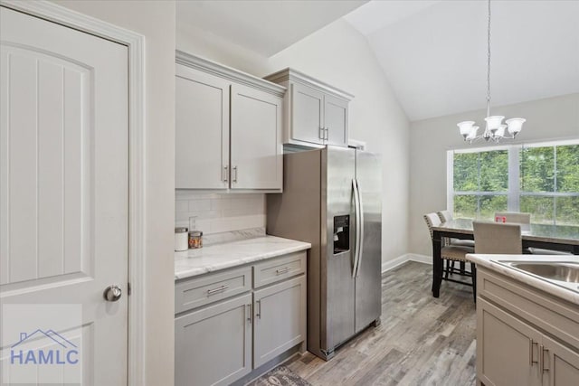 260 Linden Dr, Jesup, GA 31545 - kitchen featuring lofted ceiling, stainless steel fridge, decorative backsplash, a chandelier, and light wood-type flooring
