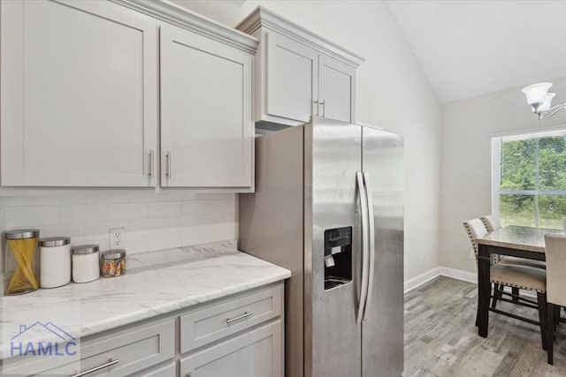 260 Linden Dr, Jesup, GA 31545 - kitchen with stainless steel refrigerator with ice dispenser, vaulted ceiling, light wood-type flooring, backsplash, and light stone counters