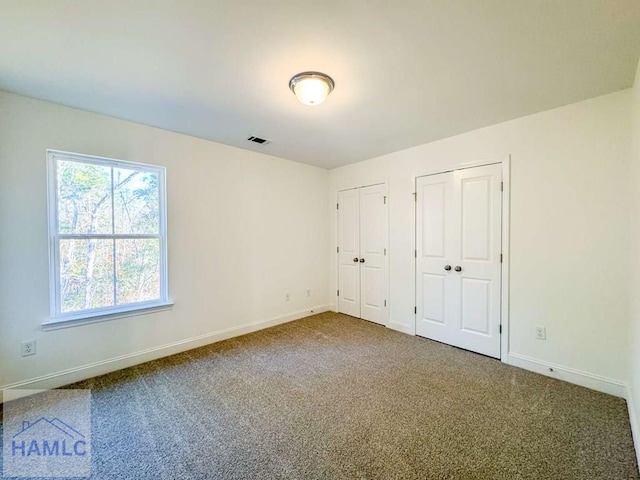 unfurnished bedroom featuring carpet and two closets