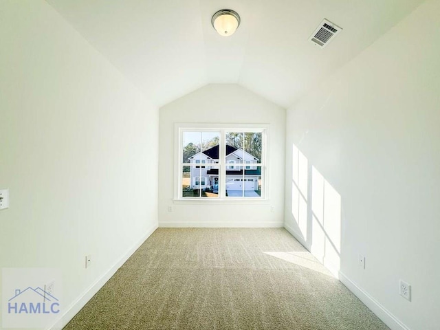 empty room featuring light colored carpet and lofted ceiling