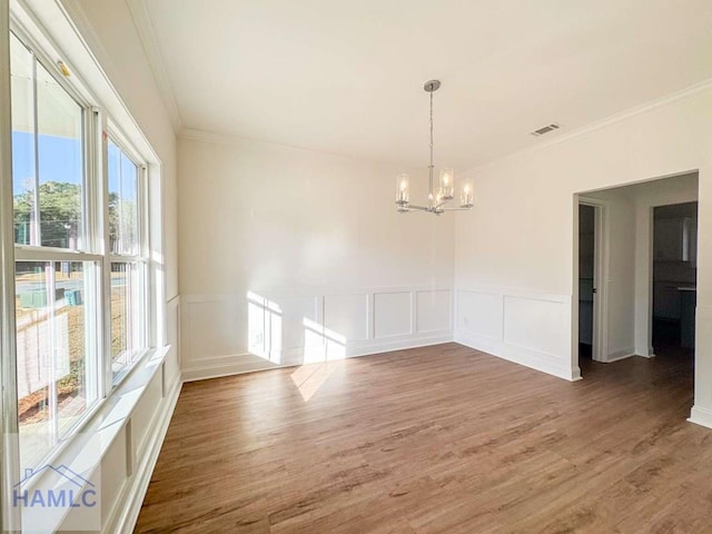 unfurnished dining area with plenty of natural light, dark wood-type flooring, a notable chandelier, and ornamental molding