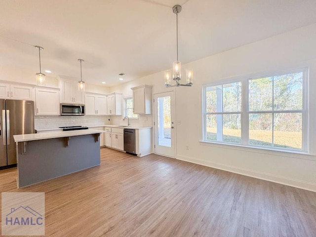 kitchen with white cabinets, pendant lighting, light wood-type flooring, and stainless steel appliances