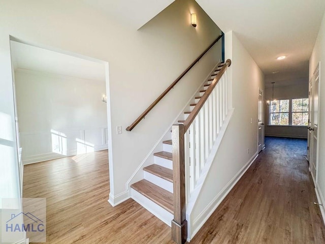 staircase with a chandelier and wood-type flooring