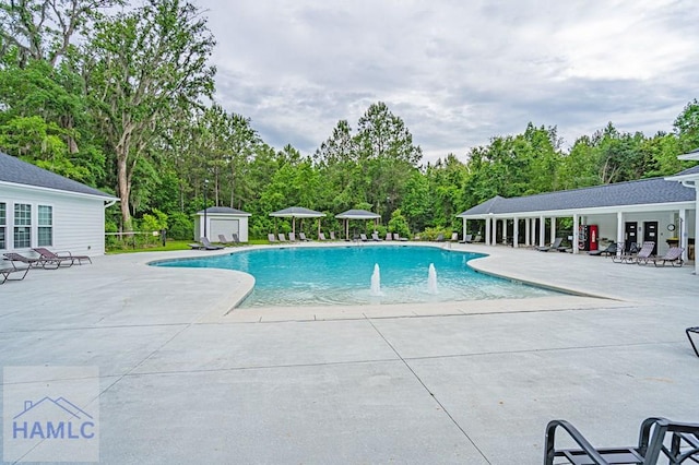 community pool with a patio area, a storage unit, and an outdoor structure