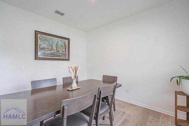 dining area with light wood-type flooring and baseboards