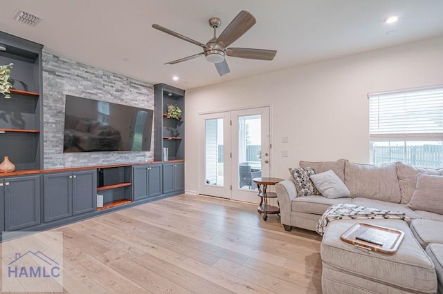 living room with light wood-style floors, a ceiling fan, healthy amount of natural light, built in shelves, and recessed lighting