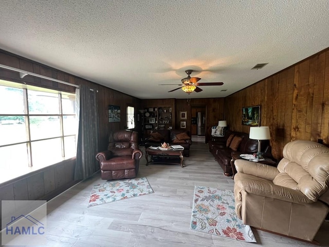 224 Bacon St, Jesup, GA 31545 - living area featuring wooden walls, a textured ceiling, ceiling fan, and light wood finished floors