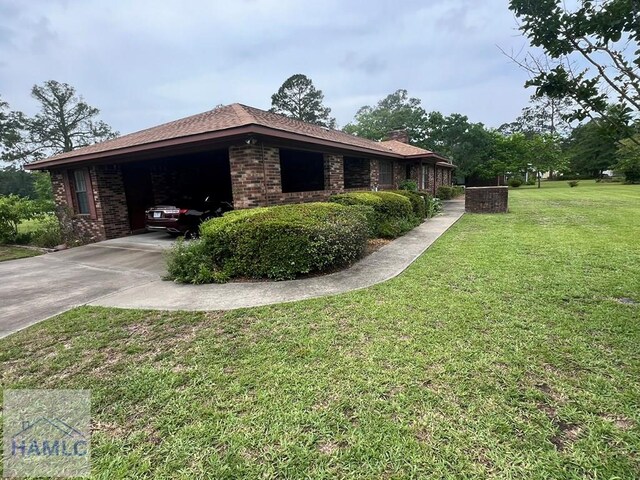 224 Bacon St, Jesup, GA 31545 - view of home's exterior with a yard, an attached carport, brick siding, driveway, and a chimney