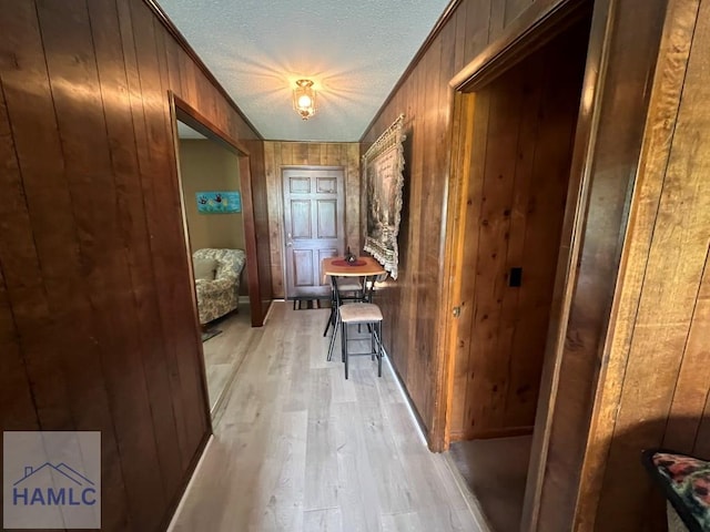 224 Bacon St, Jesup, GA 31545 - hallway featuring light wood-style floors, wooden walls, and a textured ceiling