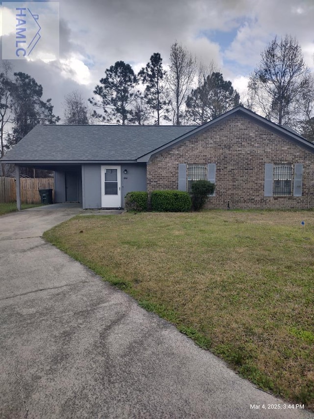 view of front of home featuring aphalt driveway, brick siding, fence, a carport, and a front lawn