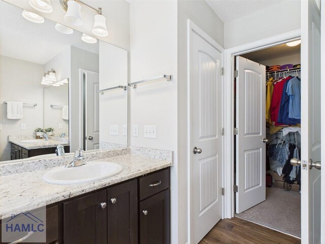 full bath with a spacious closet, wood finished floors, and vanity