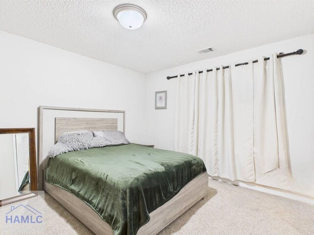 carpeted bedroom with a textured ceiling and visible vents