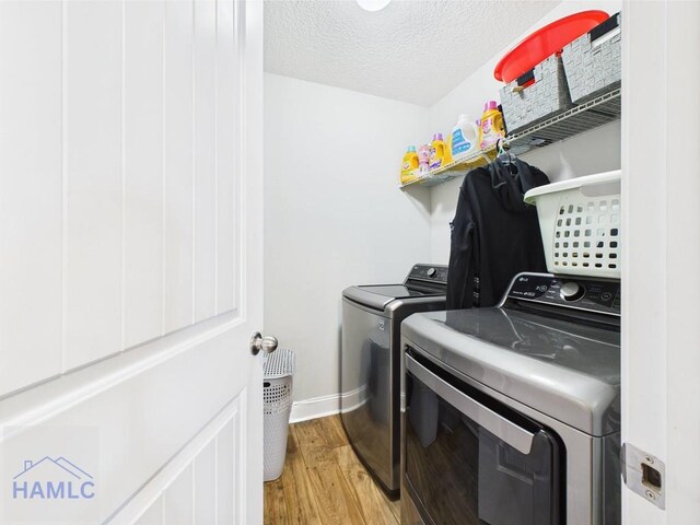 laundry area with laundry area, washing machine and dryer, baseboards, light wood-type flooring, and a textured ceiling