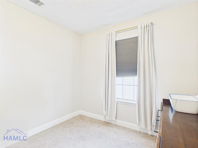 carpeted spare room with baseboards and visible vents