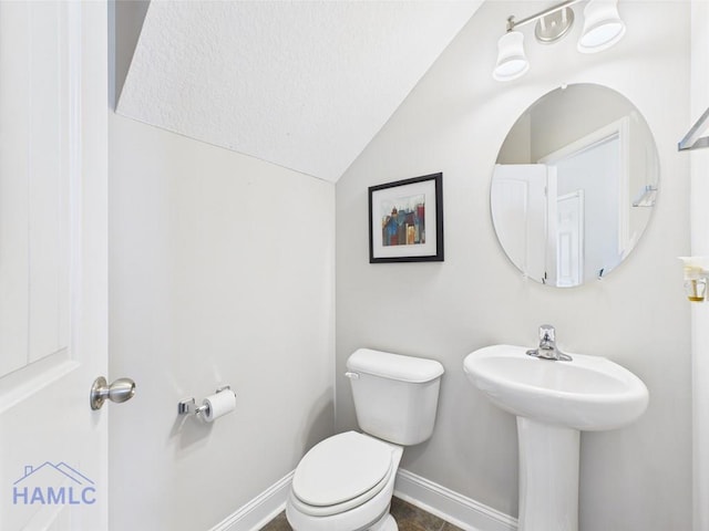 half bathroom featuring baseboards, lofted ceiling, and toilet