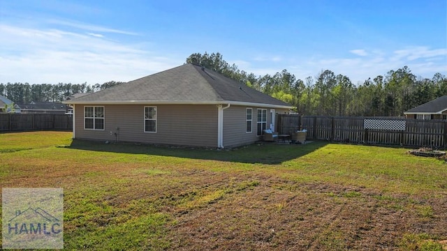 back of property featuring a lawn, a fenced backyard, and a shingled roof