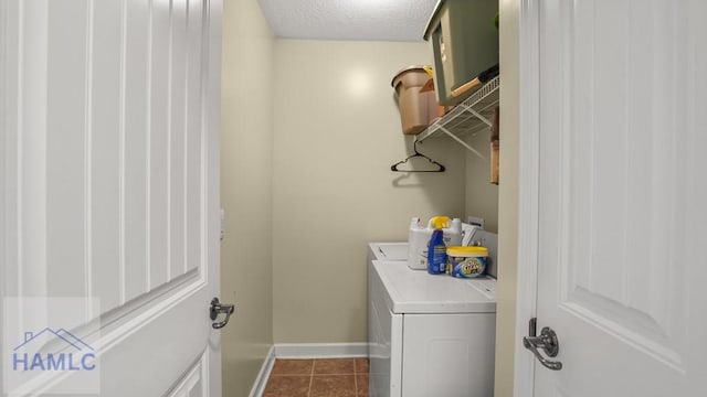 laundry room featuring dark tile patterned floors, washer and dryer, a textured ceiling, baseboards, and laundry area