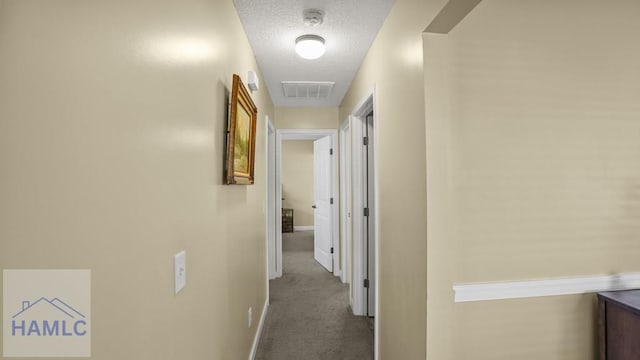 hallway featuring visible vents, carpet flooring, a textured ceiling, and baseboards