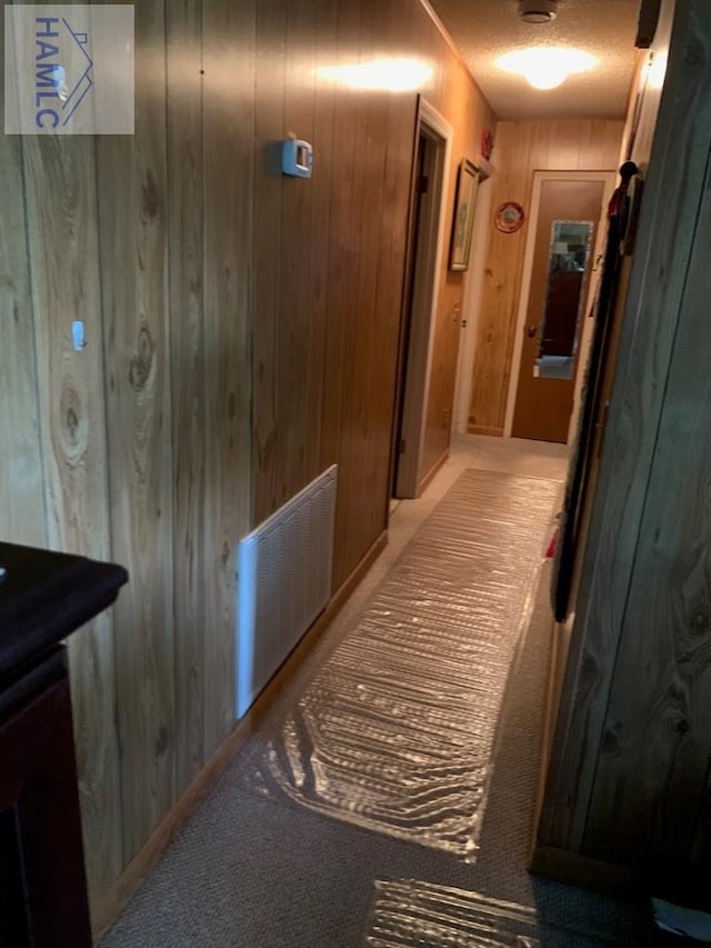 corridor with a textured ceiling and wooden walls