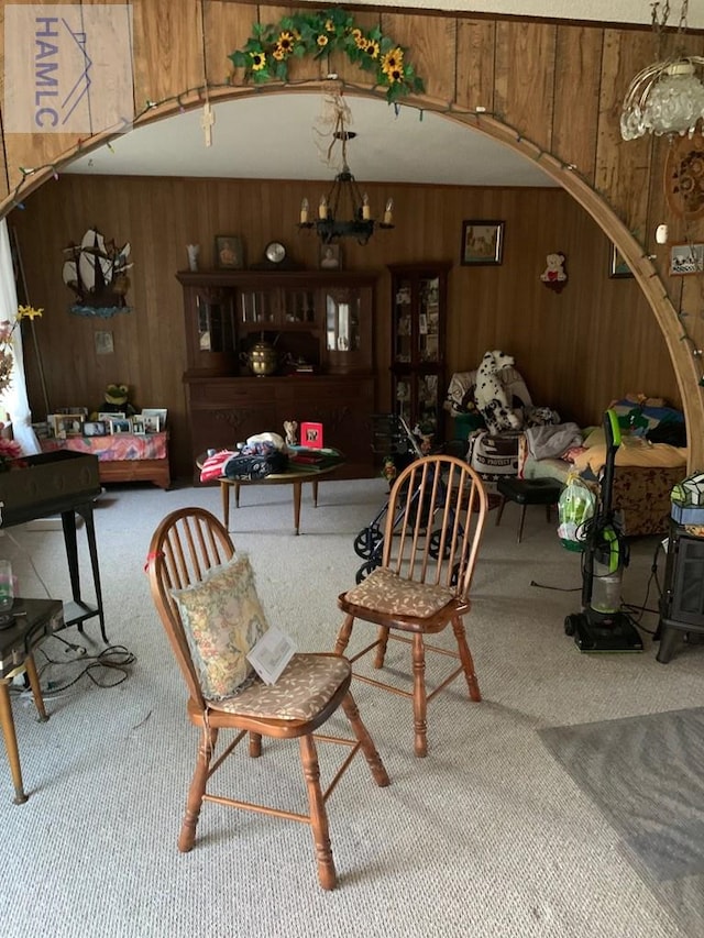 dining area featuring a notable chandelier, carpet floors, and wooden walls