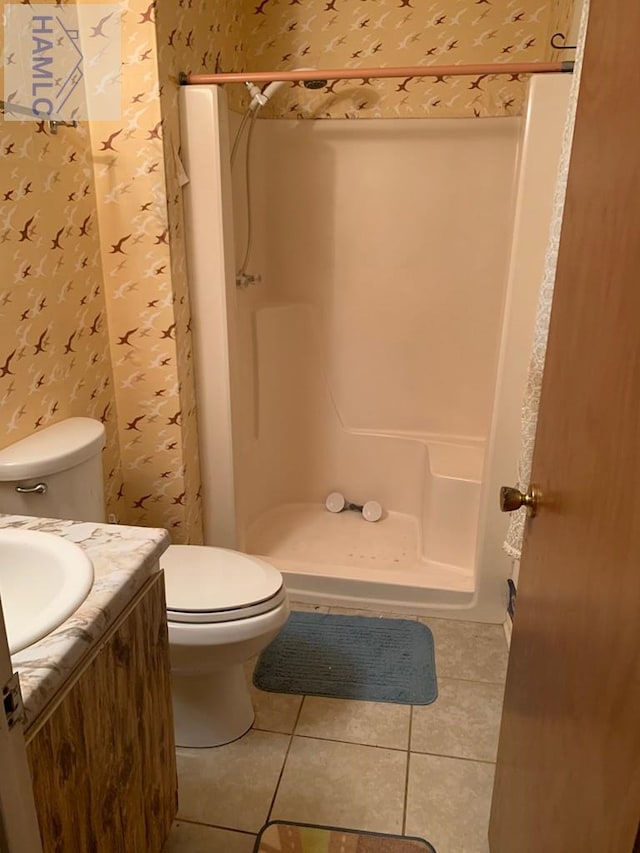 bathroom with tile patterned floors, toilet, vanity, and walk in shower