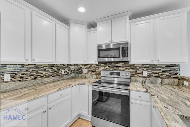 kitchen featuring backsplash, light stone countertops, white cabinets, and stainless steel appliances