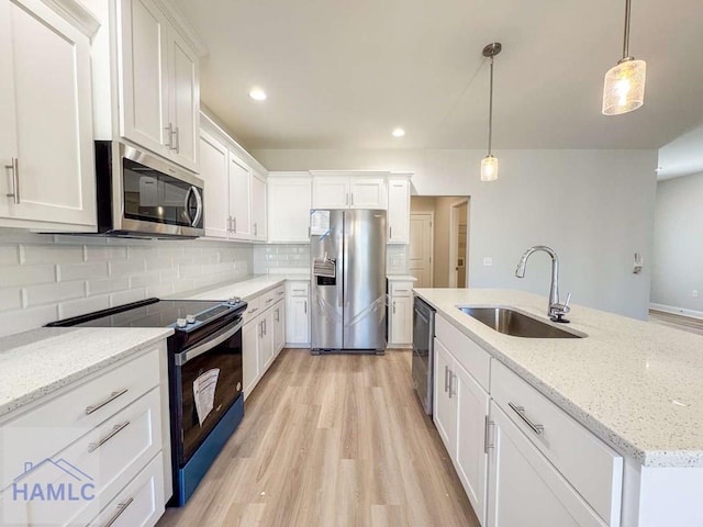 kitchen with sink, appliances with stainless steel finishes, an island with sink, pendant lighting, and white cabinets