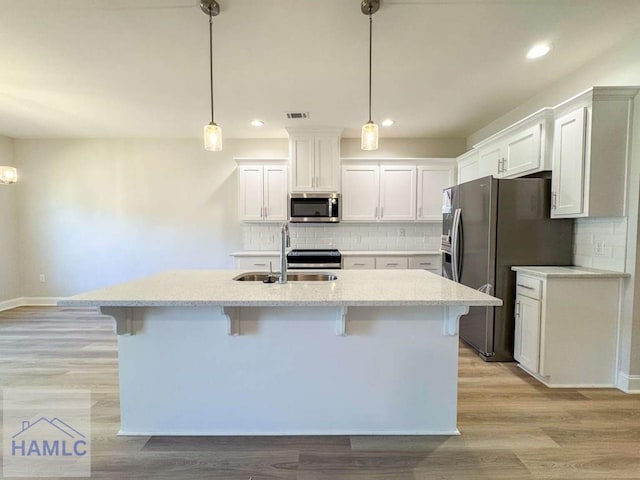 kitchen with hanging light fixtures, white cabinetry, and appliances with stainless steel finishes