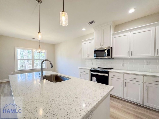 kitchen featuring white cabinetry, sink, hanging light fixtures, a kitchen island with sink, and black range with electric cooktop