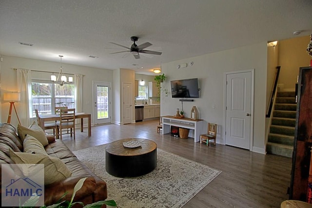 living room with wood-type flooring, ceiling fan with notable chandelier, and a textured ceiling