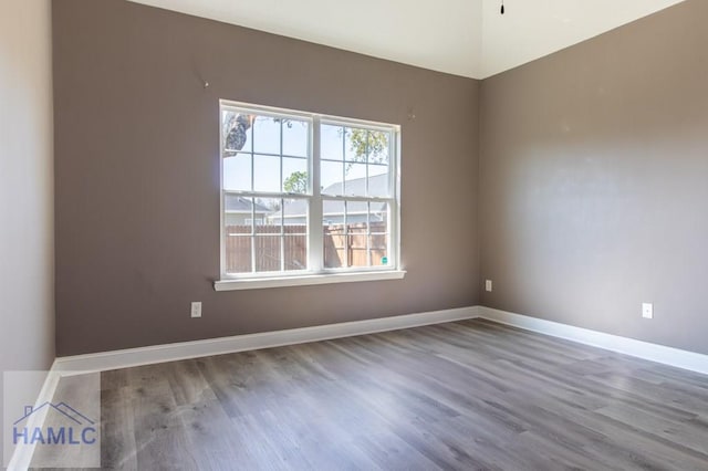 spare room with baseboards and wood finished floors