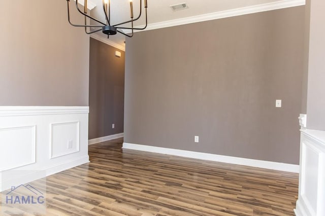 unfurnished dining area featuring visible vents, crown molding, wood finished floors, a notable chandelier, and a decorative wall