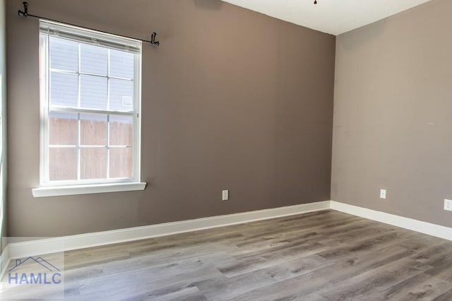 unfurnished room featuring wood finished floors, baseboards, and a healthy amount of sunlight