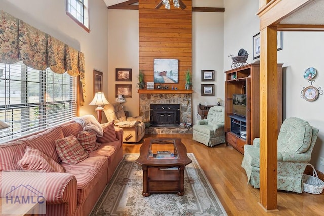 living room with a fireplace, hardwood / wood-style flooring, plenty of natural light, and a high ceiling