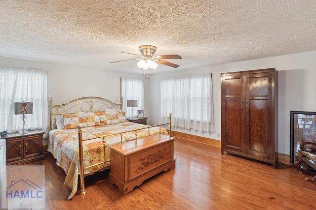 bedroom with ceiling fan, a textured ceiling, and light wood-type flooring