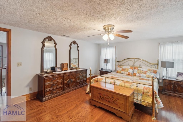 bedroom with a textured ceiling, ceiling fan, and light wood-type flooring