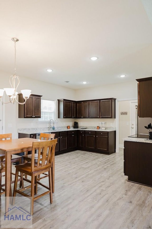 kitchen featuring an inviting chandelier, sink, light wood-type flooring, decorative light fixtures, and dark brown cabinetry