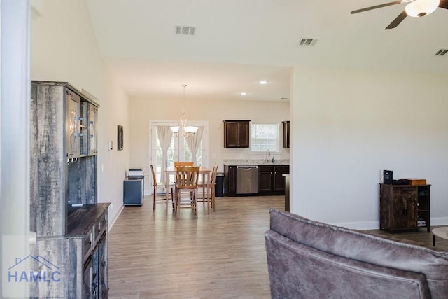 living room with ceiling fan with notable chandelier, light hardwood / wood-style floors, and sink