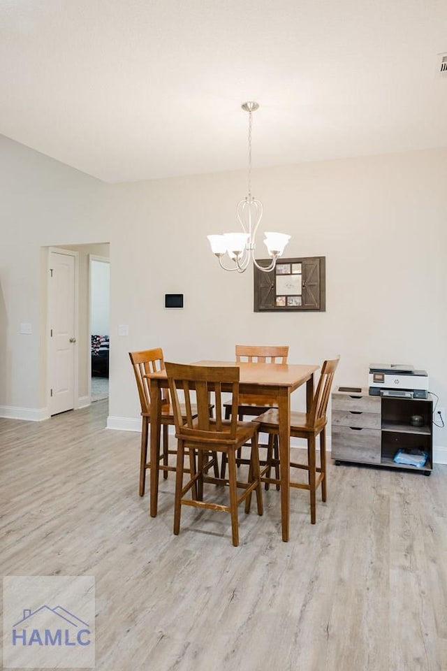 dining space with light hardwood / wood-style flooring and a notable chandelier