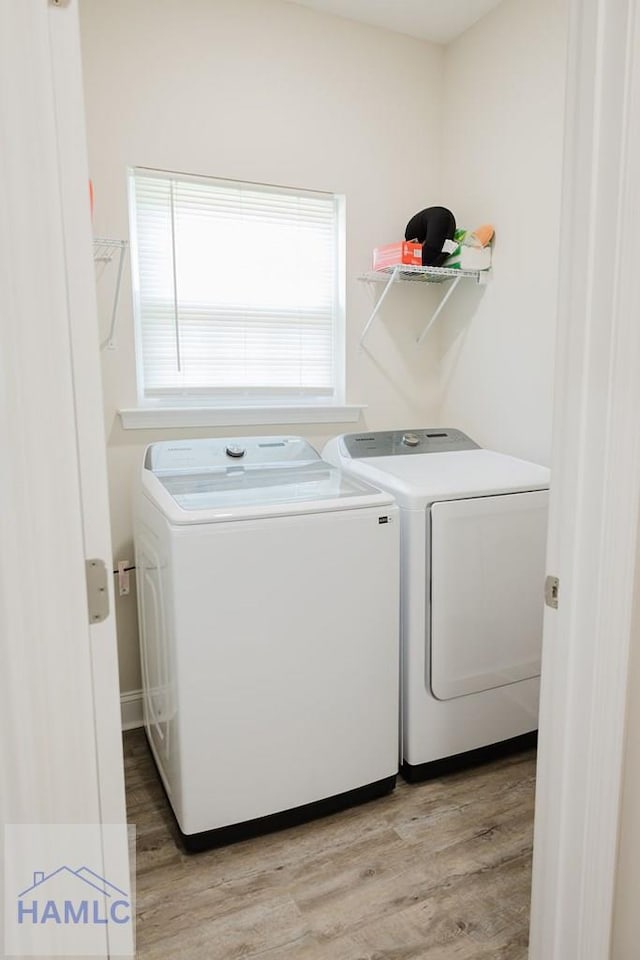 washroom with washing machine and dryer and light hardwood / wood-style flooring