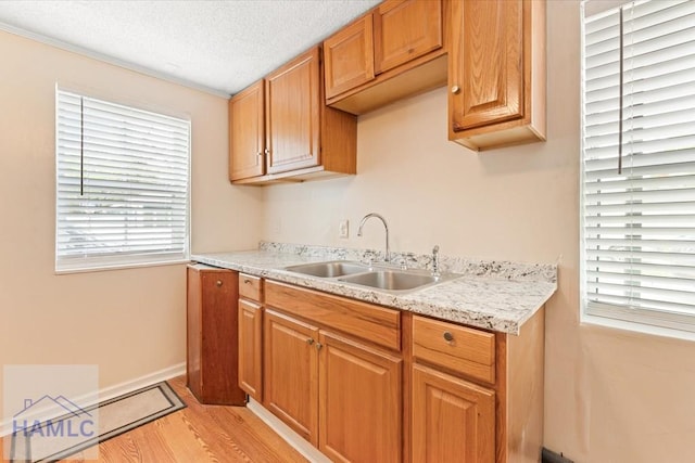 1514 Augusta Ave, Savannah, GA 31415 - kitchen with baseboards, light wood-style flooring, a textured ceiling, and a sink