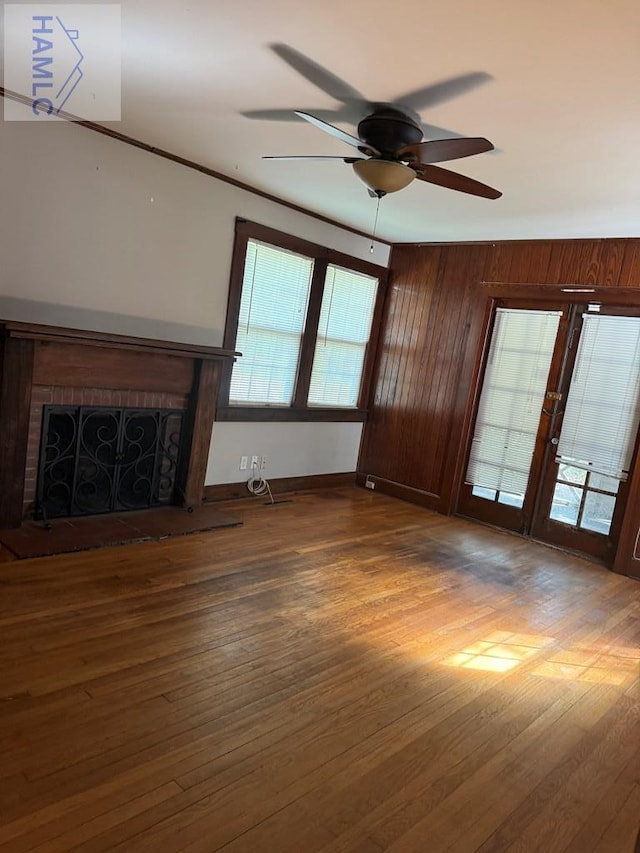 147 S Elm St, Jesup, GA 31545 - unfurnished living room with a fireplace with raised hearth, ceiling fan, wood finished floors, and wood walls