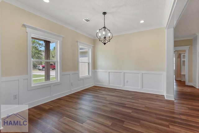 unfurnished dining area featuring wainscoting, visible vents, an inviting chandelier, crown molding, and dark wood-type flooring