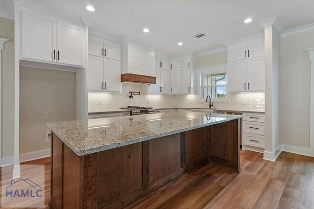 kitchen with visible vents, baseboards, custom exhaust hood, white cabinetry, and wood finished floors