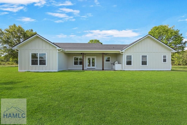 rear view of house with a lawn, a ceiling fan, board and batten siding, and french doors