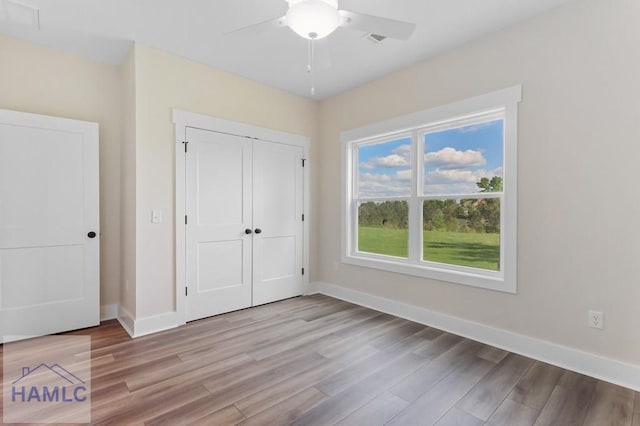 unfurnished bedroom with baseboards, visible vents, light wood finished floors, and a closet