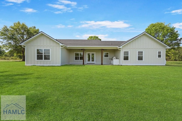 rear view of property with board and batten siding, ceiling fan, french doors, and a yard